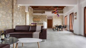 A modern living room with a brown leather sofa, a glass coffee table, and a dining area with a wooden table and chairs.