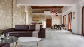 Uma sala de estar moderna com um sofá de couro marrom, uma mesa de centro de vidro e uma área de jantar com mesa e cadeiras de madeira.