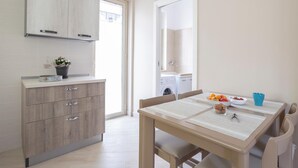 Una cocina moderna con armarios de madera, una mesa de comedor con sillas y vistas a un área de lavandería.