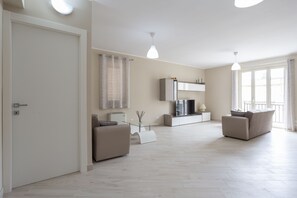 A modern living room with a sofa, a glass coffee table, and a TV. - Sicano Home (Delia)