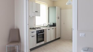 Una cocina moderna con armarios de madera clara, una estufa a gas, un horno y un lavamanos.