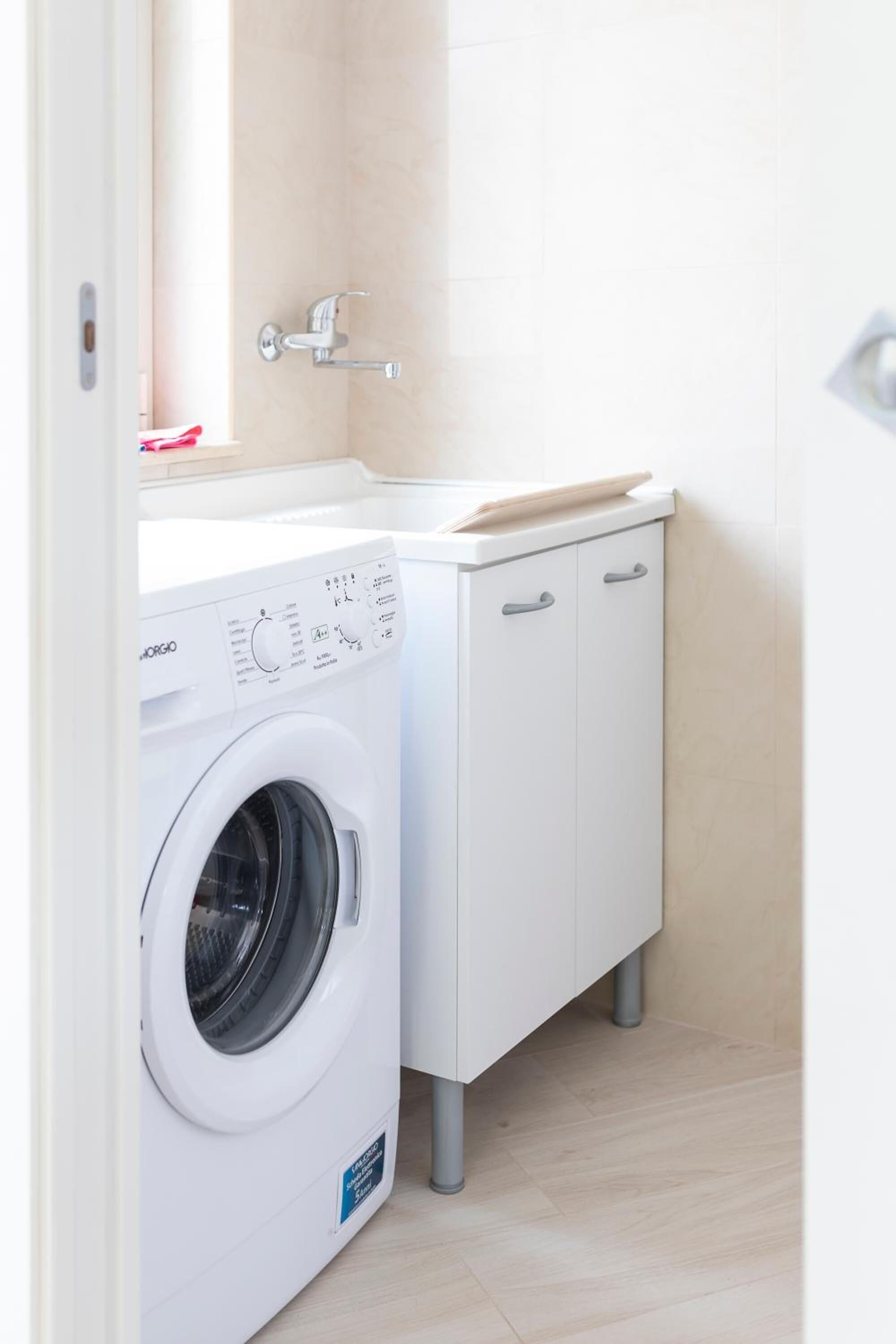 A compact laundry area with a front-loading washing machine and a cabinet with a sink.