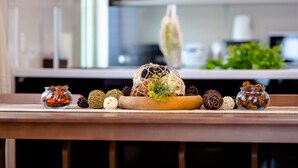 Uma mesa de madeira com objetos decorativos, incluindo uma cesta trançada, pinhas e pequenos frascos.