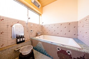 A bathroom with a bathtub, a shower, and a toilet. There is a mirror above the sink and a window with an air conditioner above it. - Fujisan-Kingyo (Fujikawaguchiko)