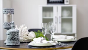 A dining table set with white plates, silverware, and clear glasses, with decorative items and a cabinet in the background. - Erable Mt.Fuji Zen (Fujikawaguchiko)