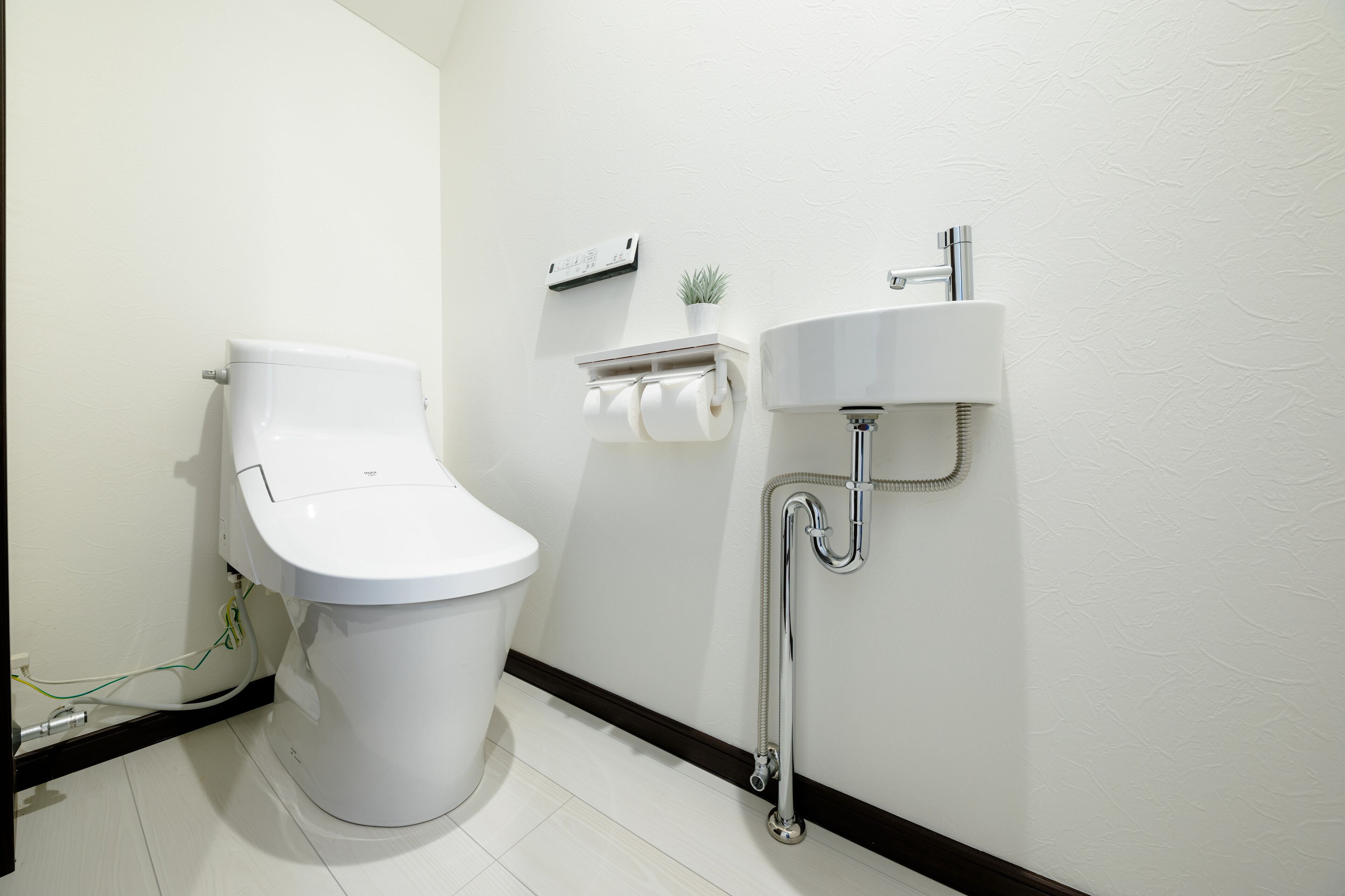 Un baño moderno con inodoro, lavabo y dispensador de papel higiénico.