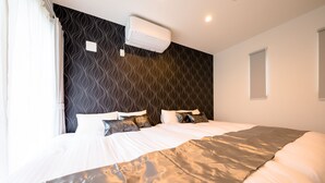 Une chambre d’hôtel moderne avec un grand lit, un climatiseur fixé au mur et une fenêtre équipée de stores.