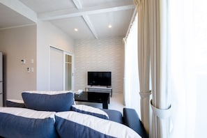 A modern hotel room with a large bed, a flat-screen TV, and a small table.
