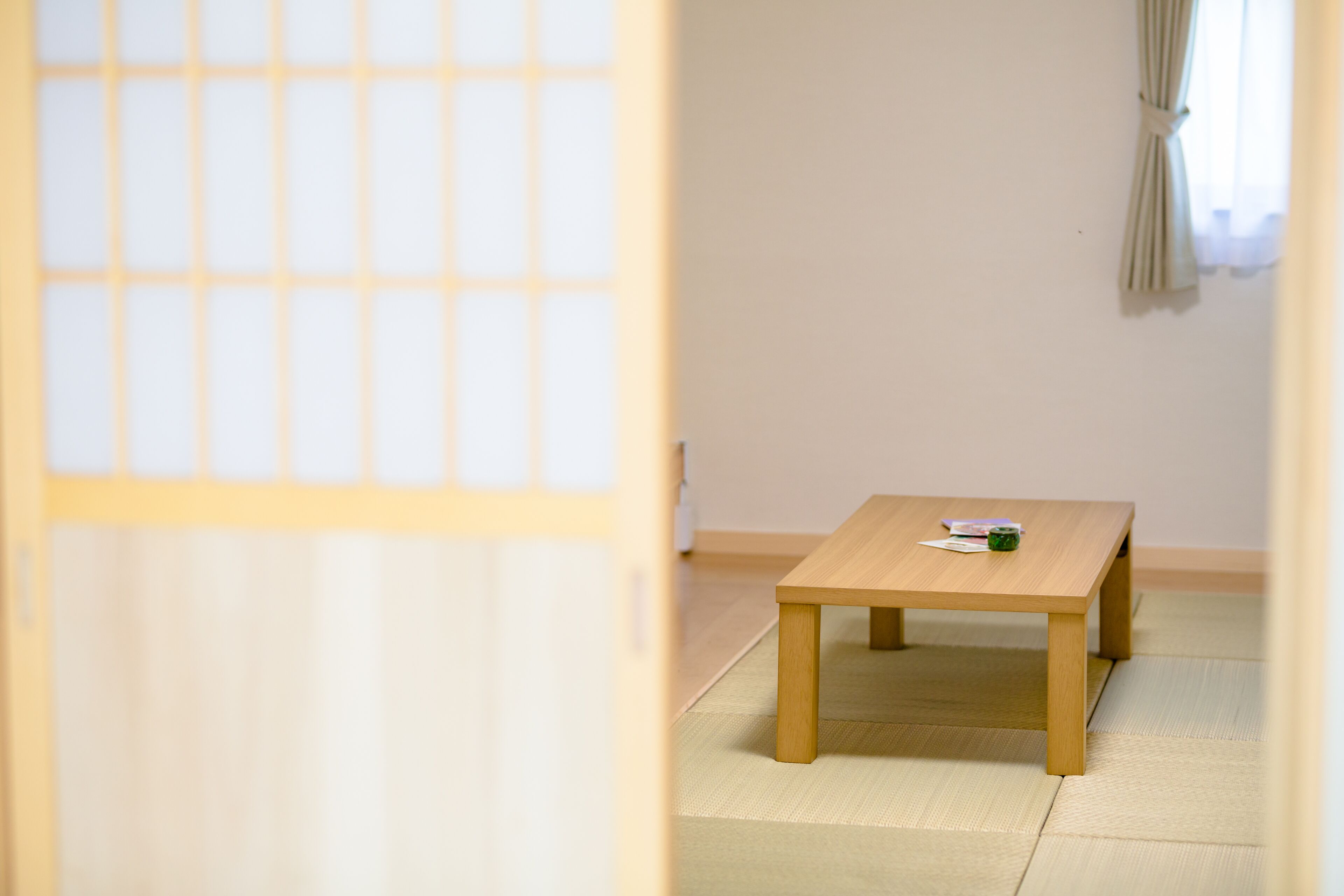 A room with tatami mat flooring, a wooden table, and a shoji screen.
