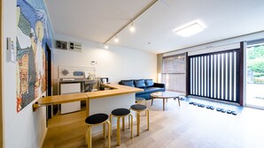 Un salon moderne comprenant un canapé, une table basse et un coin cuisine avec des tabourets.