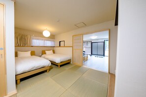 A room with two beds, tatami mats, a ceiling light, and a sliding door leading to a balcony. - The Road To Mt.Fuji (Fujiyoshida)