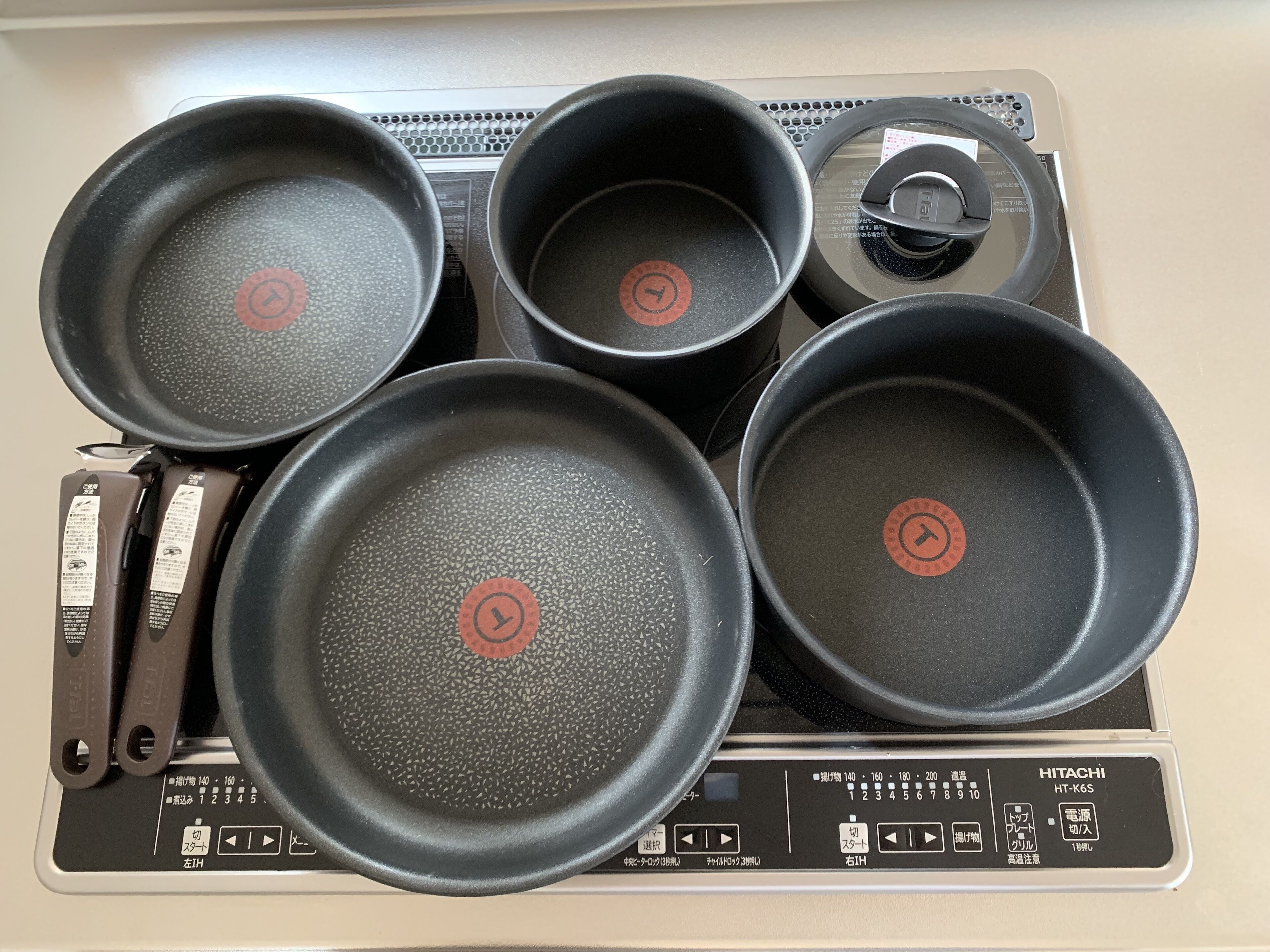 Une cuisine avec cinq poêles noires sur une cuisinière.