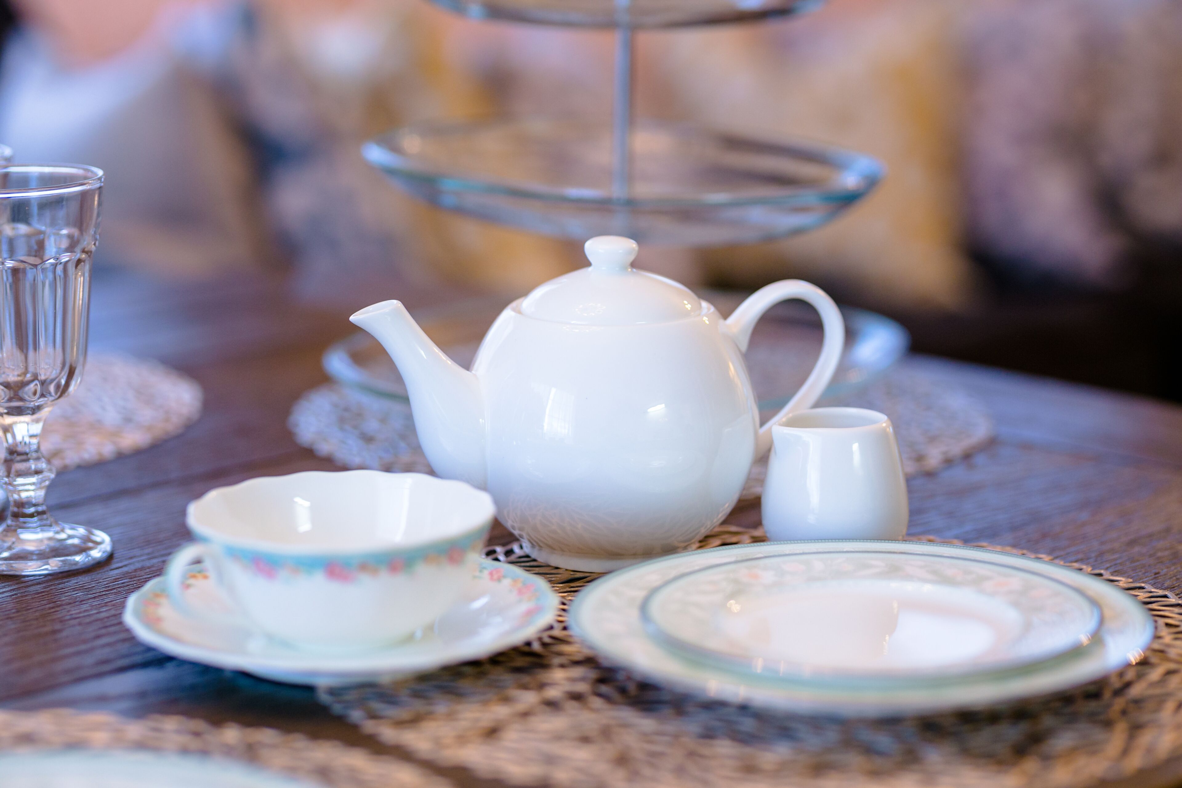 A table with a teapot, teacups, and a glass pitcher.