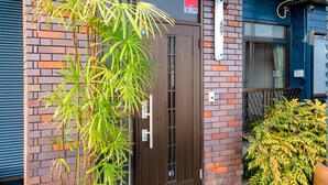 Un bâtiment avec une porte marron, une enseigne au-dessus et une petite fenêtre.