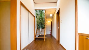 Un couloir avec un plancher en bois, une plante posée sur une étagère et un extincteur.