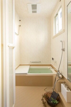 A small, modern bathroom with a bathtub, a shower, and a window.