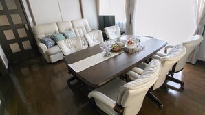 Ein Essbereich mit einem Holztisch, weiß gepolsterten Stühlen und einer Couch mit blauen Kissen.