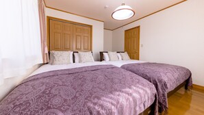 A bedroom with two beds, a wooden wardrobe, and a ceiling light.