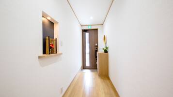 A narrow hallway with wooden flooring, white walls, and a door at the end.