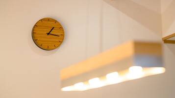A wooden wall clock with a minimalist design, mounted on a plain wall.