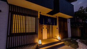 A modern building with a dark facade, a signboard with "FUJI-AKATSUKI" text, and two lit lanterns on the steps. - Mt. Fuji Akatsuki Enn (Fujikawaguchiko)