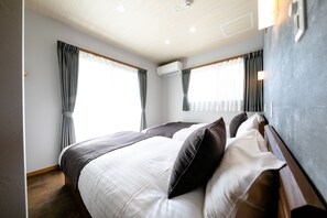 A modern hotel room with a large bed, two windows with curtains, an air conditioning unit, and a wooden headboard. - Oriya Mt.Fuji -Enishi- (Fujikawaguchiko)
