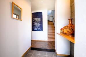 A hallway with a wooden floor, a mirror on the left, a blue tapestry on the wall, and a wooden staircase in the background. - Oriya Mt.Fuji -Enishi- (Fujikawaguchiko)