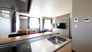 A modern kitchen with a built-in oven, a stainless steel sink, and a flat-screen TV mounted on the wall. - Oriya Mt.Fuji -Enishi- (Fujikawaguchiko)