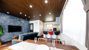 A modern living room with a dining area, a kitchen in the background, and a large window with curtains. - Oriya Mt.Fuji -Nishiki- (Fujikawaguchiko)