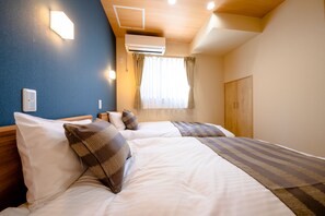 A hotel room with two beds, a wooden ceiling, an air conditioner, a window with curtains, and a wardrobe.