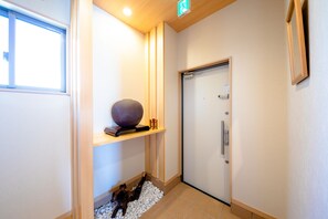 A hallway with a door, a shelf with a decorative item, and a dog on the floor.
