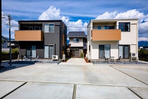 A modern residential area with two-story houses featuring balconies, outdoor seating, and a clear sky.