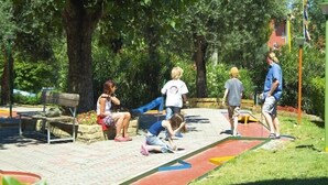 A park with a paved walkway, benches, and trees.