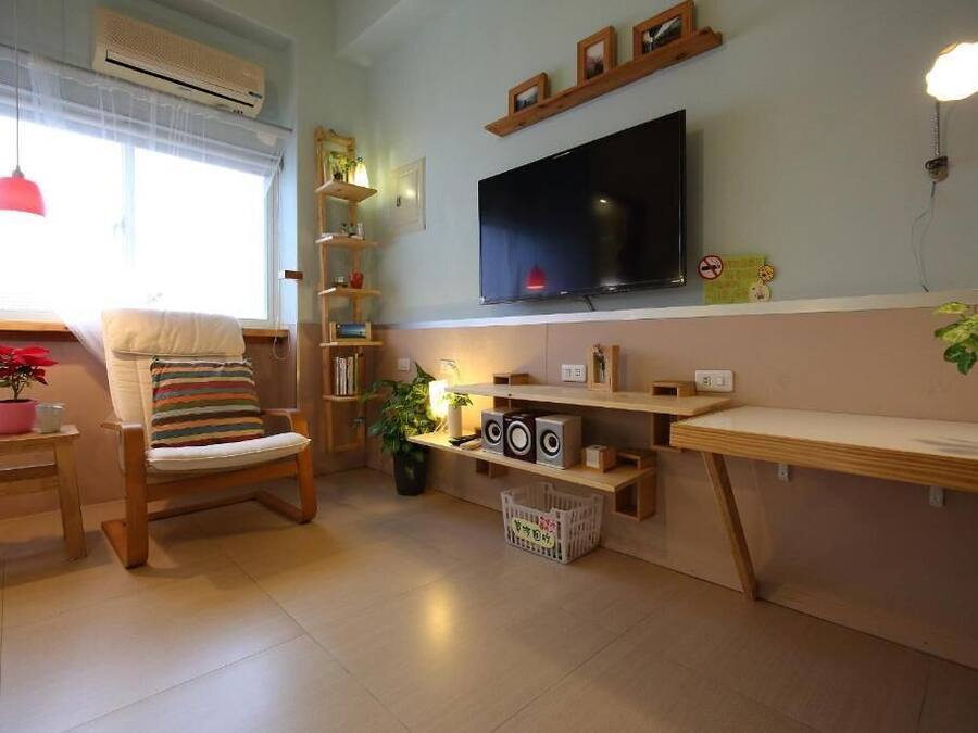 A living room with a TV, shelves, a chair, and a small table with a plant.
