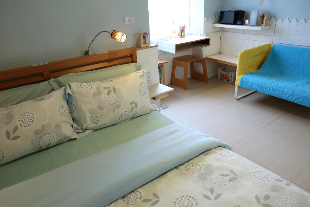 A bedroom with a bed, a desk, a chair, and a TV.