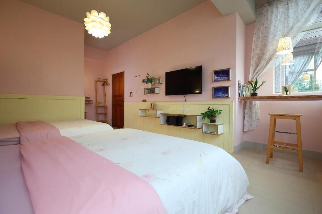 A bedroom with a bed, a TV, and a window with curtains.