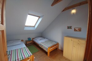 Ein kleiner, gemütlicher Raum mit zwei hölzernen Betten, einem Holzschrank, einem Oberlicht und einem Nachttisch mit Lampe.