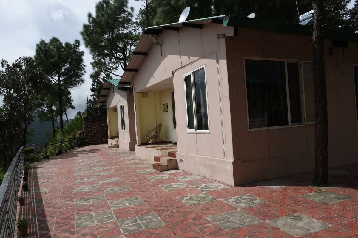 A two-story building with a tiled patio, a satellite dish, and a staircase leading to the upper floor.