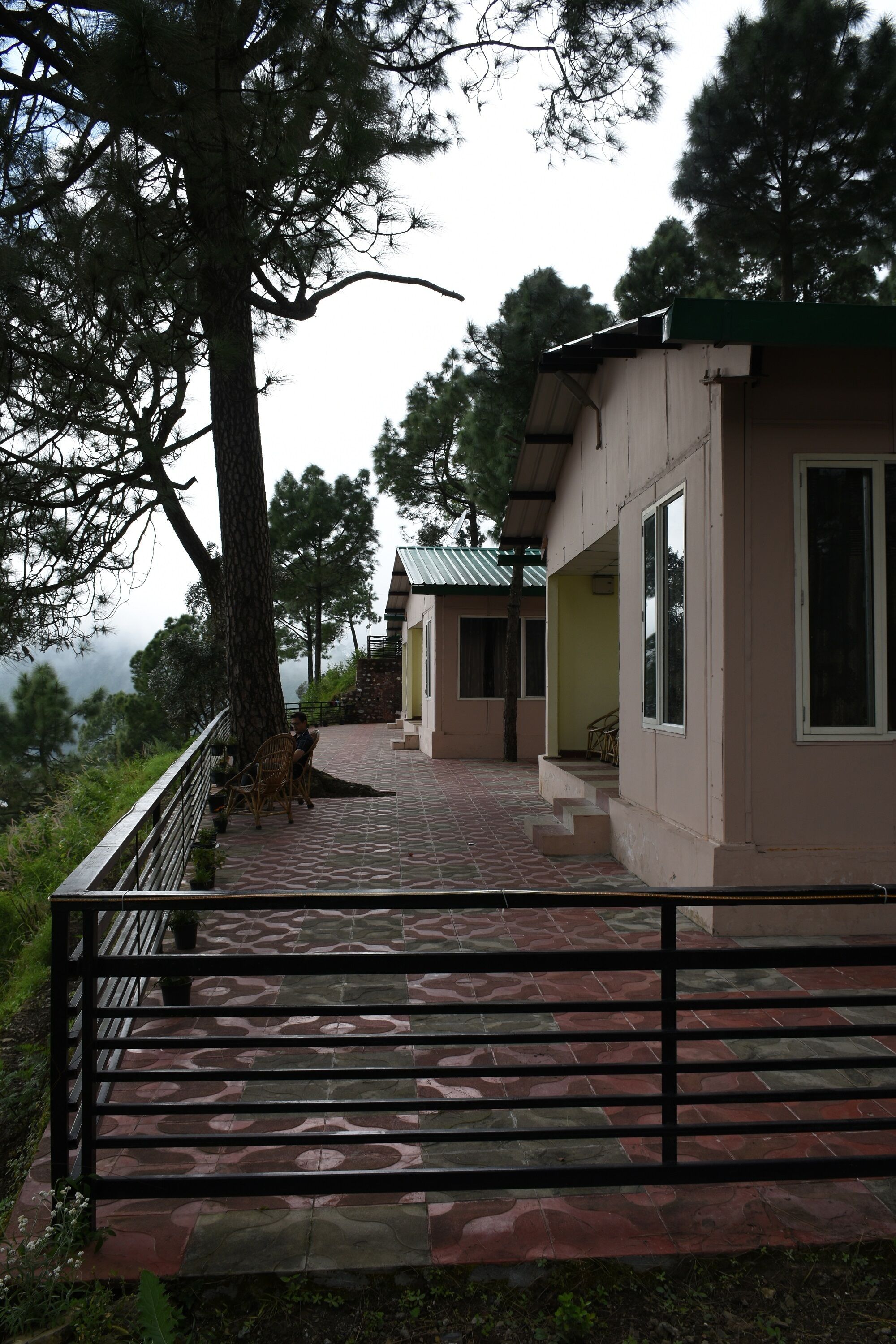 Un edificio con una scala che conduce a un portico, circondato da alberi e una vista sul paesaggio.