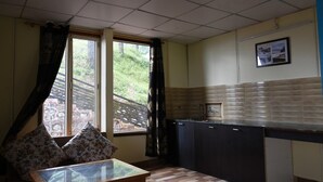 A small kitchen with a window, a table, and a sofa. - The Moksha Heights (Nainital)
