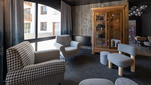 A modern interior with houndstooth patterned chairs, a grey ottoman, and a wooden cabinet with glass doors. - Cristal Lodge by Daddy Pool - TerresenS (Saint-Chaffrey)