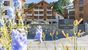 A multi-story lodge with a stone wall entrance, wooden balconies, and a sign reading "CRISTAL LODGE TERRÉS". - Cristal Lodge by Daddy Pool - TerresenS (Saint-Chaffrey)