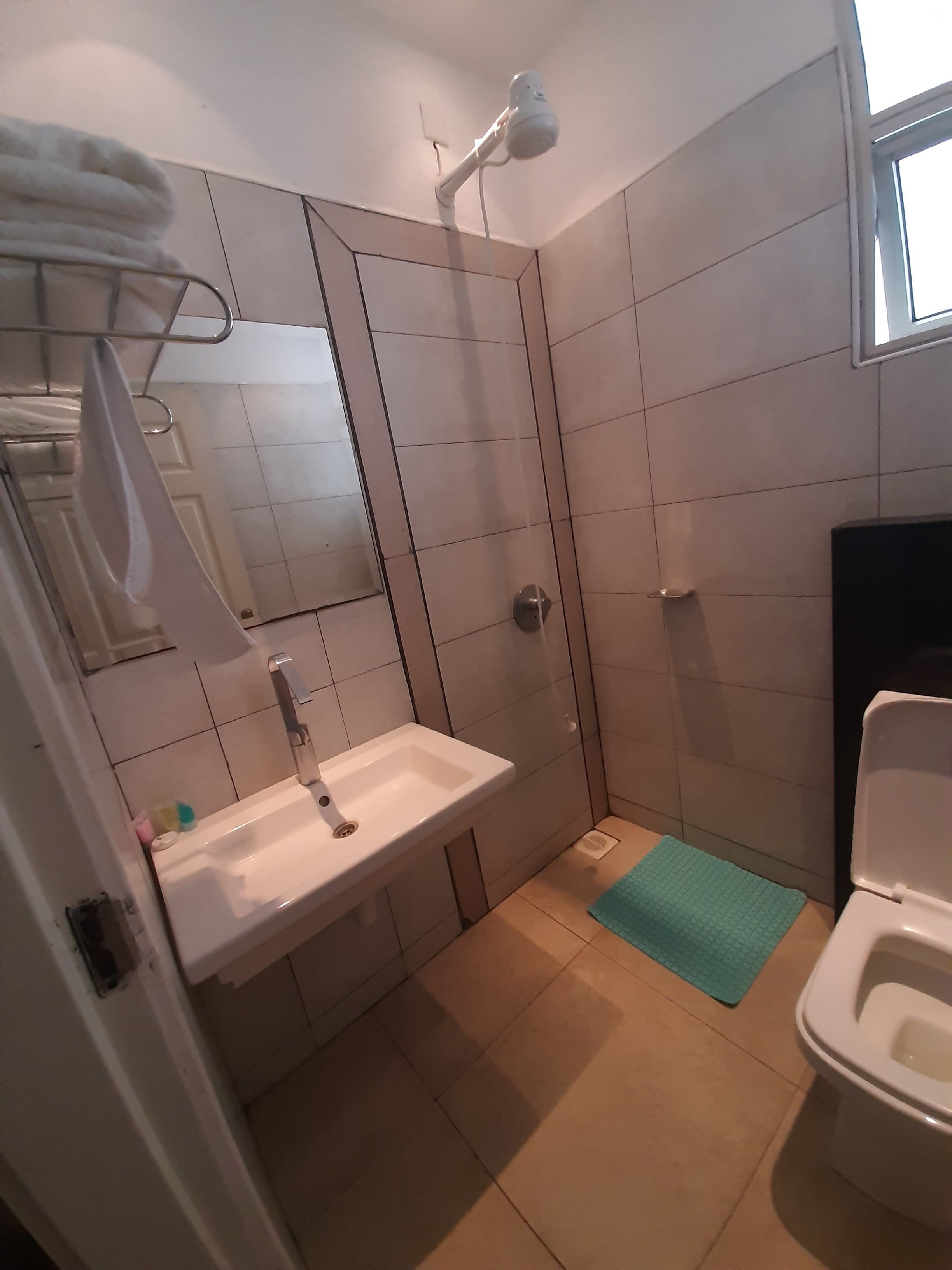 A bathroom with a sink, mirror, towel rack, shower, and toilet.
