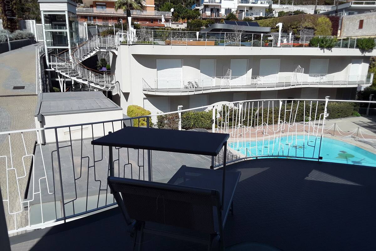 A balcony with a pool, white railings, and a table with a chair.