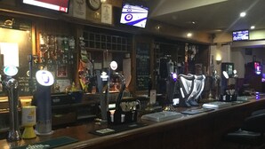 A bar with multiple beer taps, a cash register, and a chalkboard menu. - Bowmans Hotel (Goole)