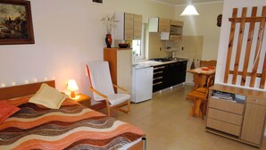 A bedroom with a bed, a chair, a desk, a small kitchen area, and a wooden cabinet. - Holiday Home in Kolczewo near Baltic Beaches (Kolczewo)