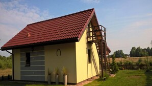 A single-story house with a red-tiled roof, a small porch, and a wooden staircase leading to a loft area. - Holiday Home in Kolczewo near Baltic Beaches (Kolczewo)