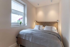 A bedroom with a bed, window, and a potted plant. - Renovierte Ferienwohnung, St. Peter-Ording (St. Peter-Ording)