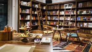 Una biblioteca acogedora con estanterías de madera, una mesa con pasteles y una alfombra estampada.