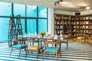 Un coin lecture confortable, avec des meubles en bois, une grande bibliothèque et une vue dégagée grâce à de grandes fenêtres.